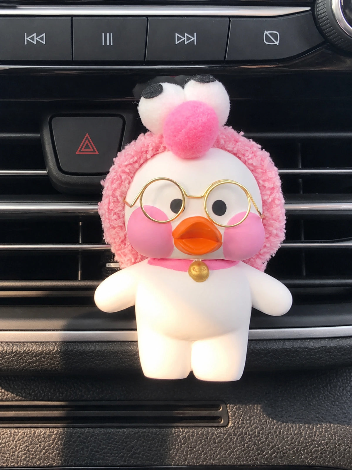 Pink Puff Duck with fuzzy pink hood, round gold glasses and gold bell on a dashboard vent