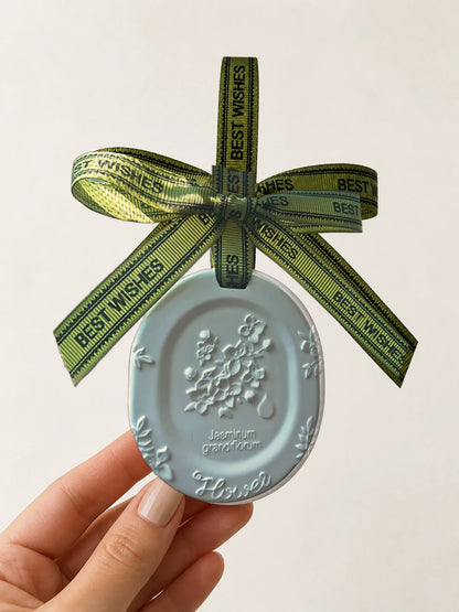 White Jasmine medallion hanging car charm shown in hand for scale
