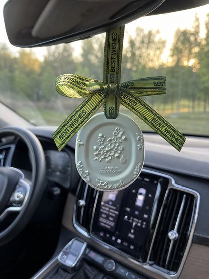 White Jasmine medallion hanging naturally beneath a Volvo rearview mirror