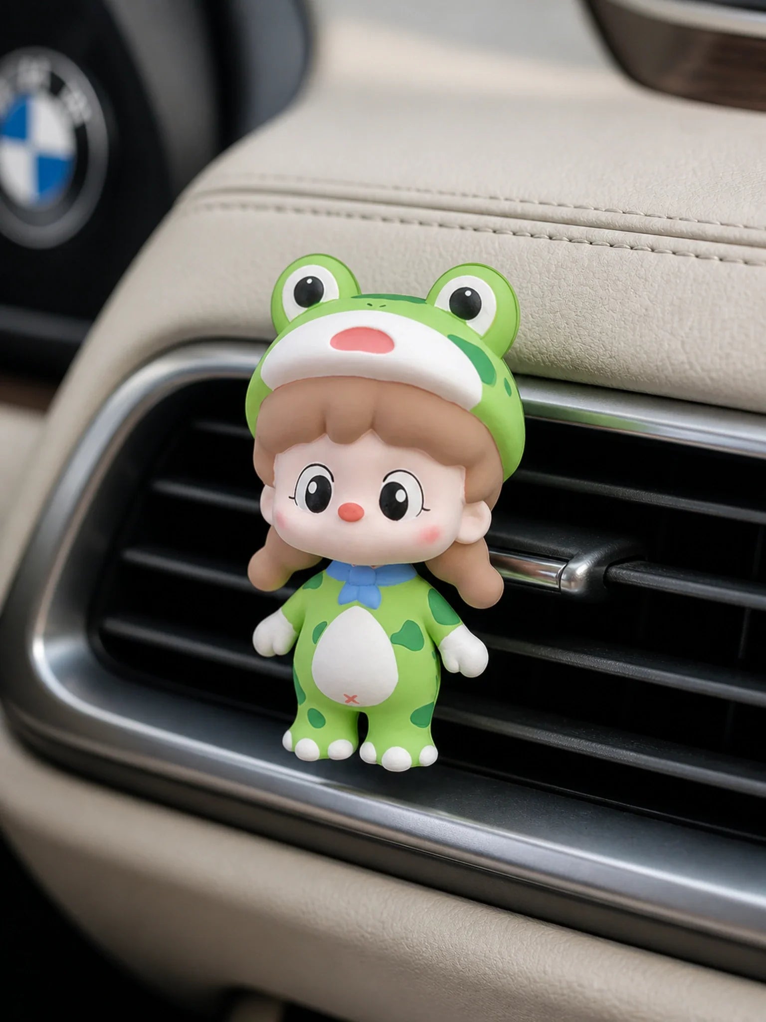 Green Frog Girl ornament mounted squarely on a BMW horizontal car vent