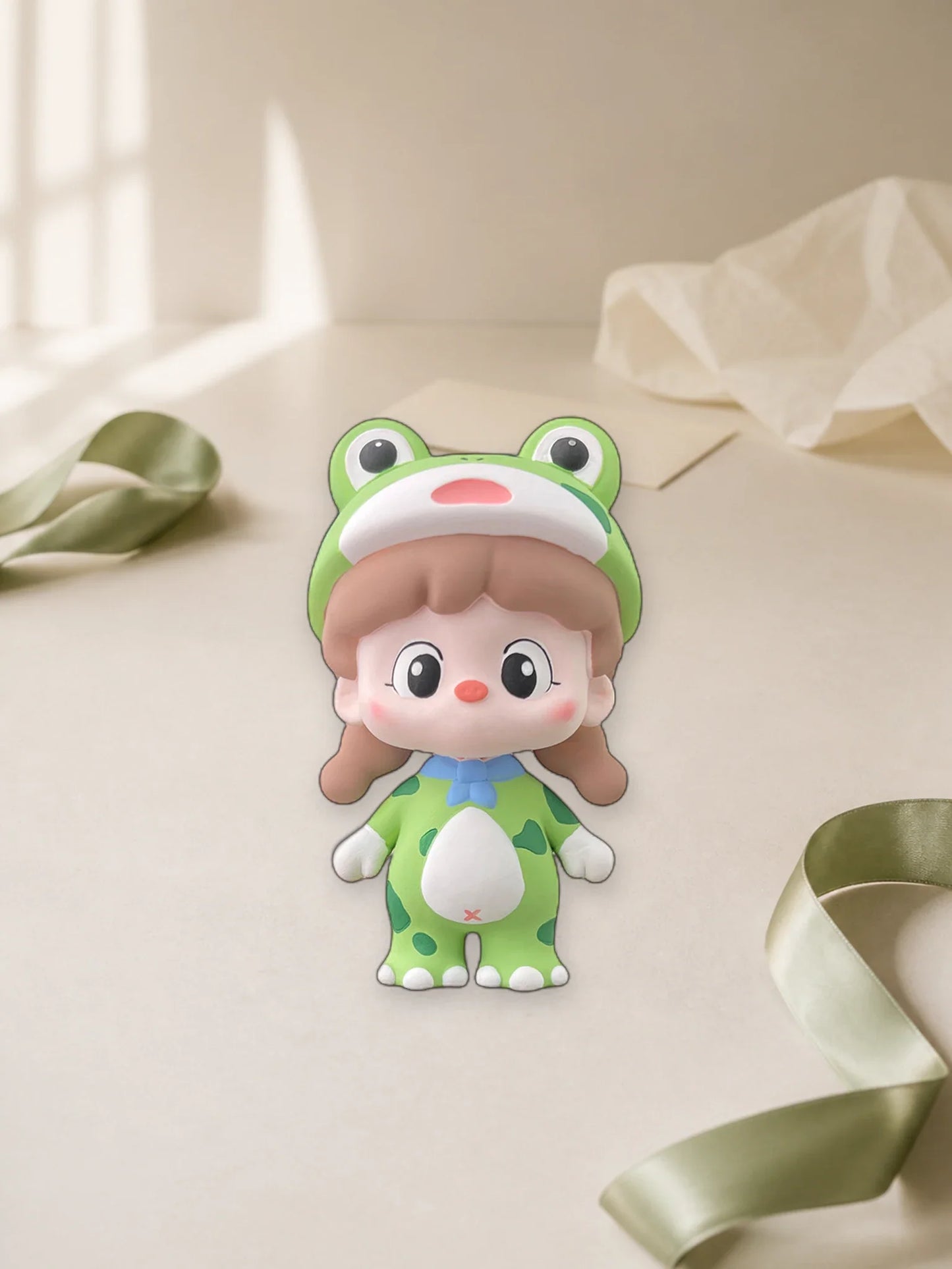 Green Frog Girl ornament presented with neutral tissue and ribbon for gifting inspiration
