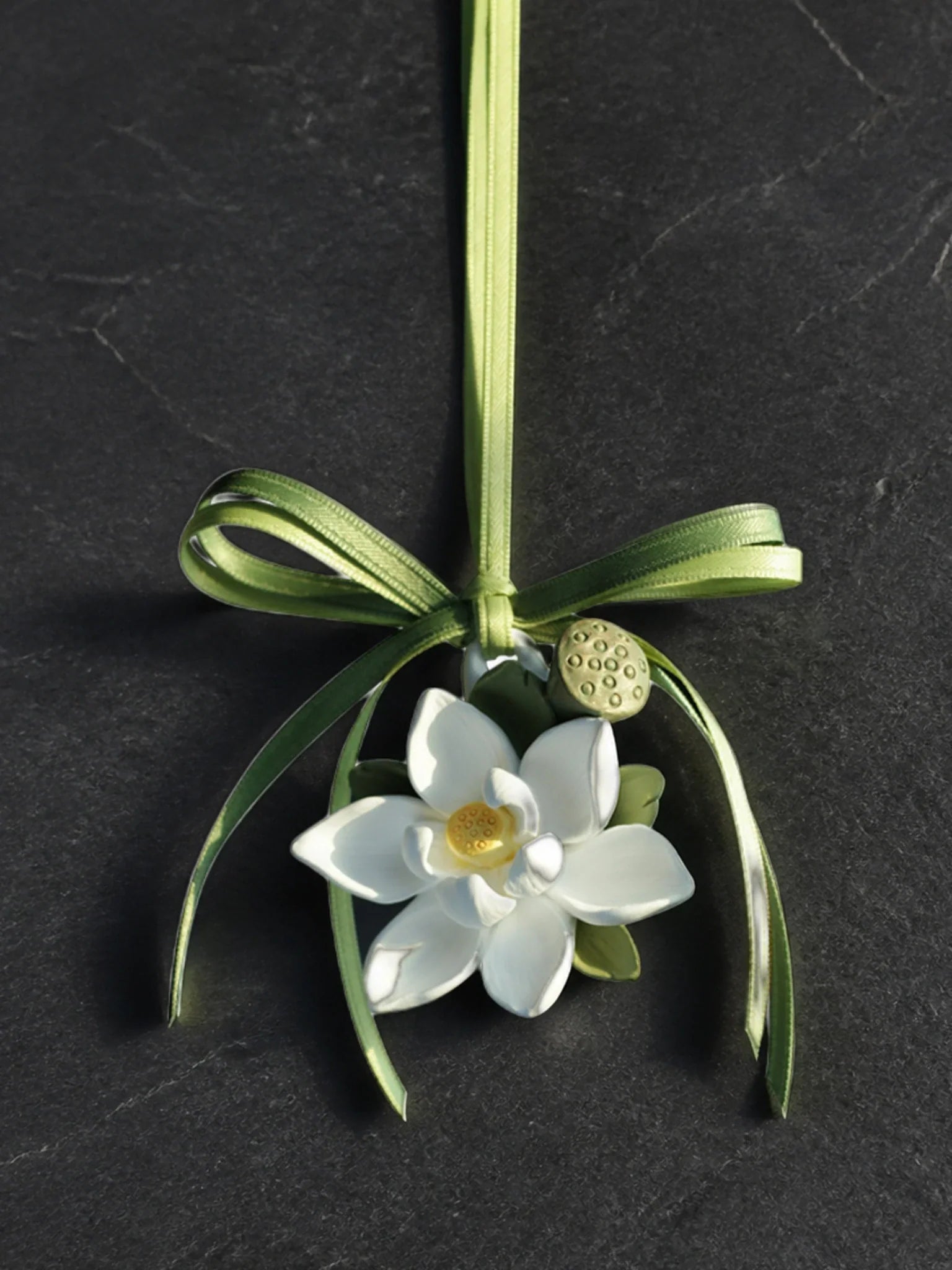 Lotus Serenity hanging car charm with original olive ribbon and botanical details on a dark surface