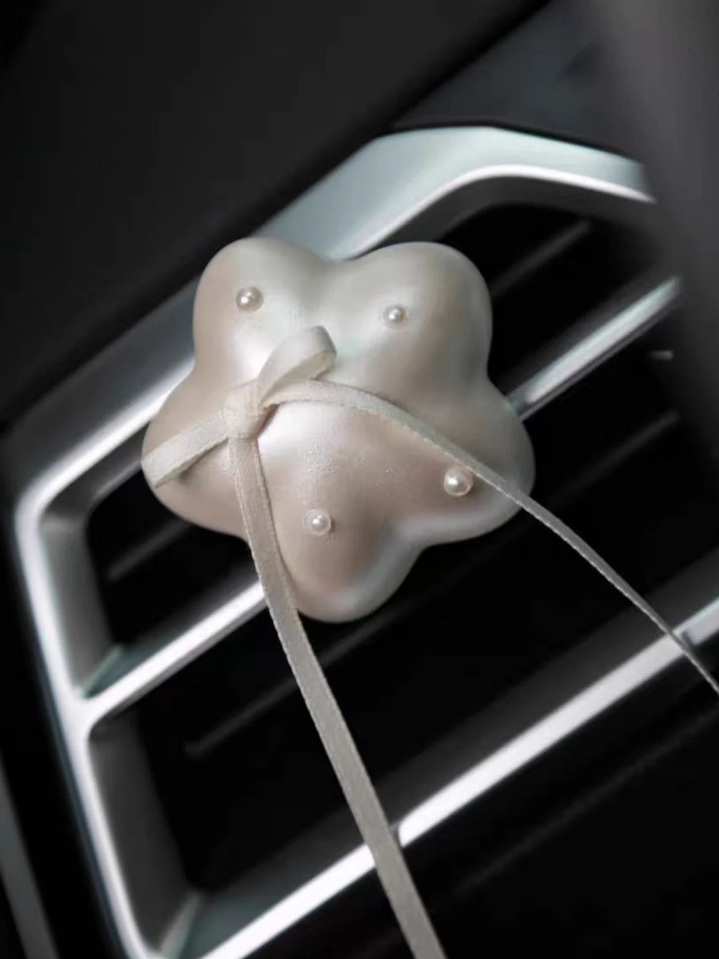 Pearl White Star car vent ornament clipped to an air vent