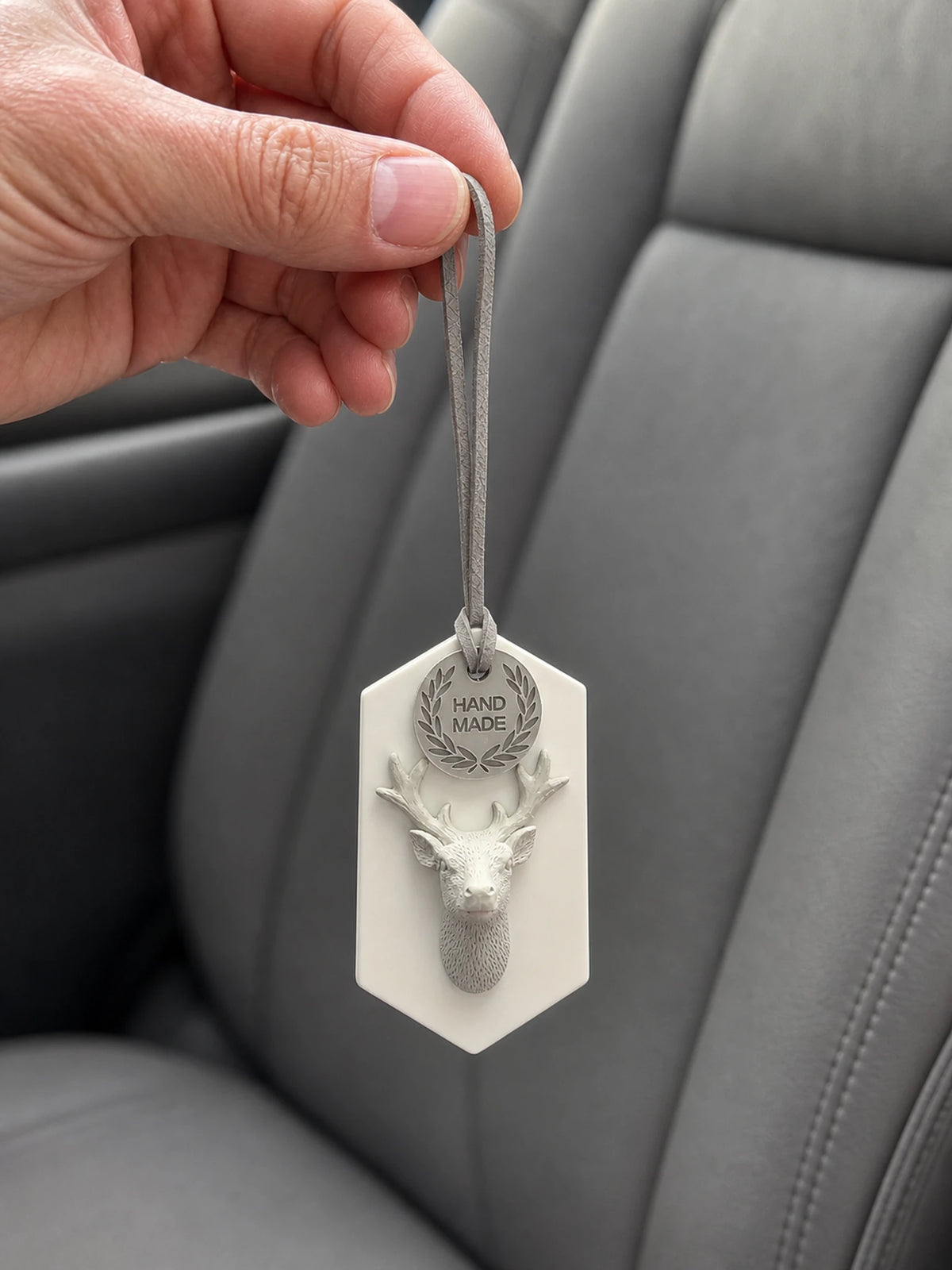 Woodland stag medallion hanging car ornament shown in hand for scale