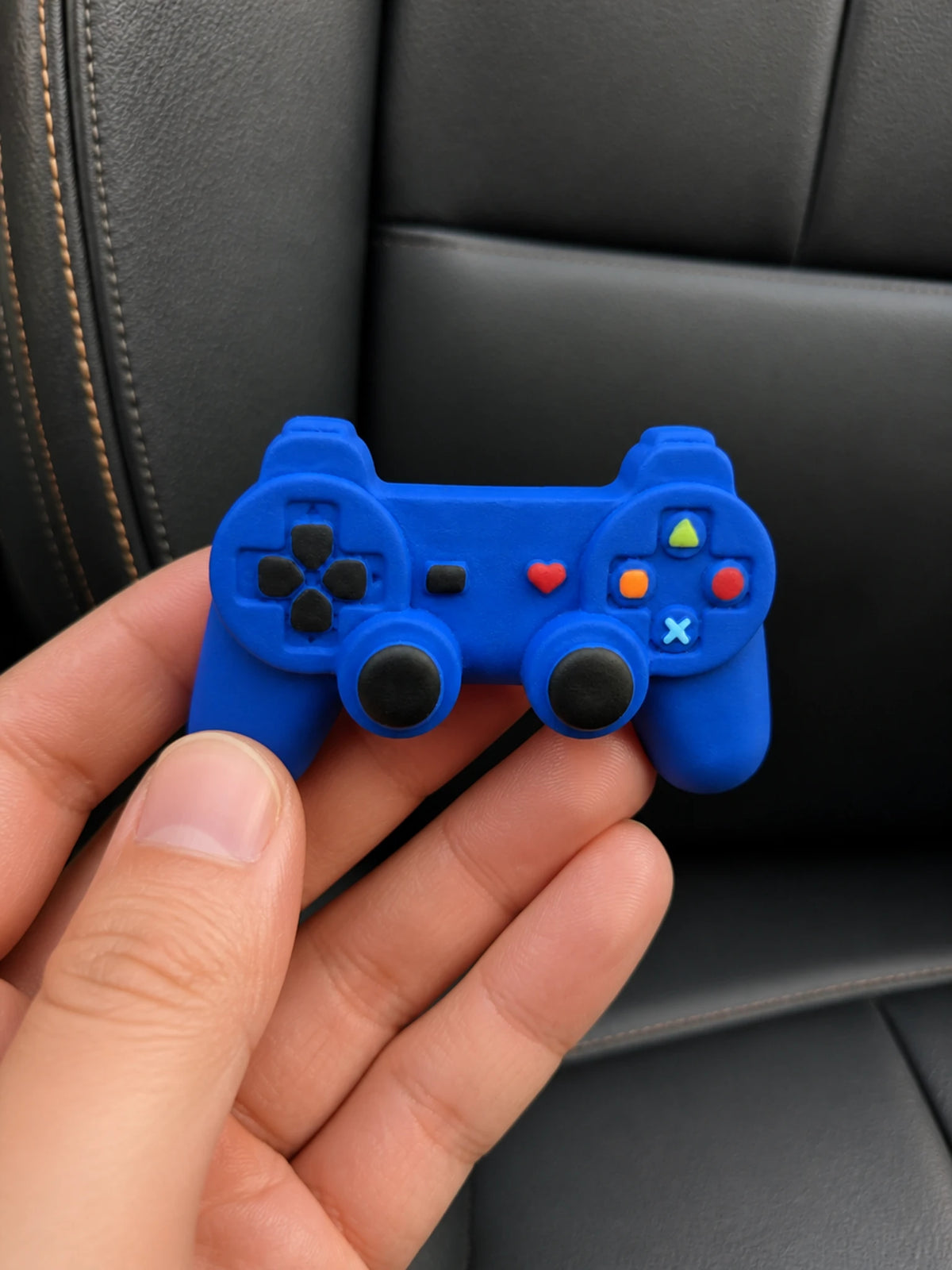 Retro game controller car vent ornament shown in hand for scale