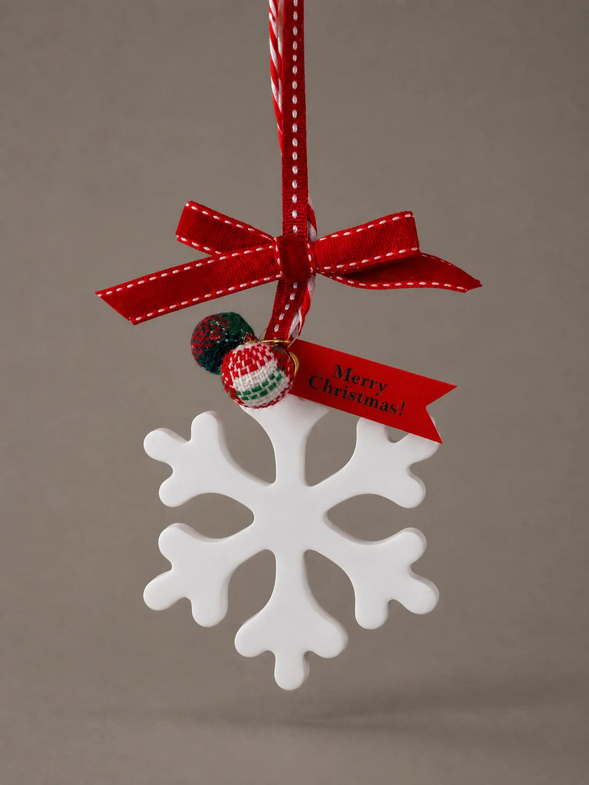 White snowflake ornament with red stitched ribbon, two tartan beads and a festive tag