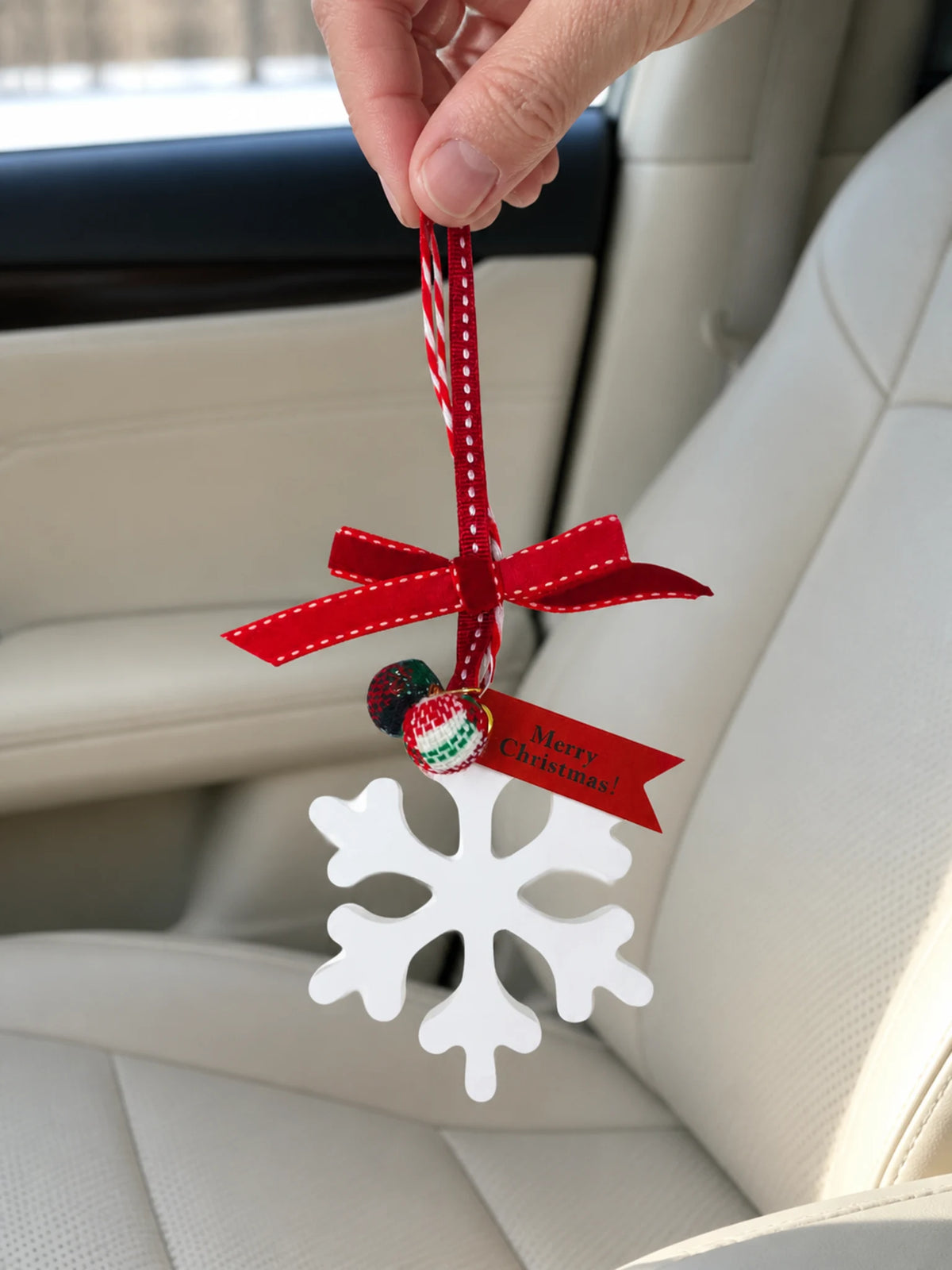 Winter snowflake hanging car ornament shown in hand for scale