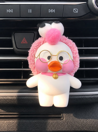 Pink Puff Duck with fuzzy pink hood, round gold glasses and gold bell on a dashboard vent