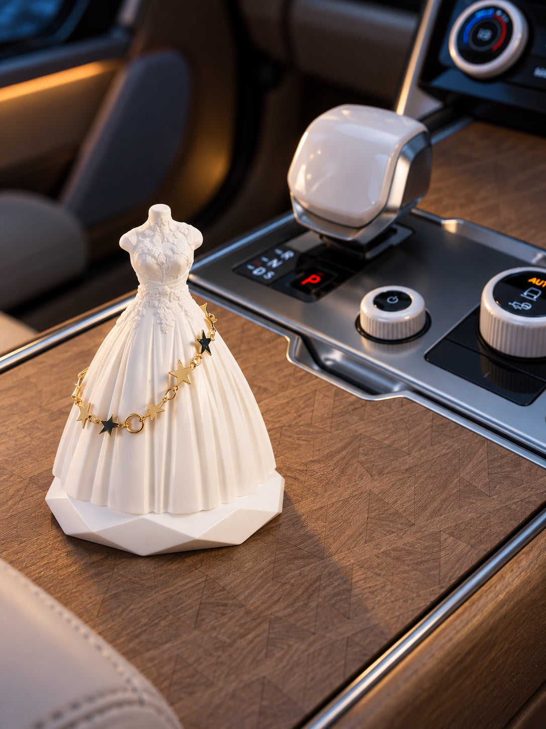 White bridal silhouette ornament on the closed level wood lid of a parked Range Rover SV at dusk