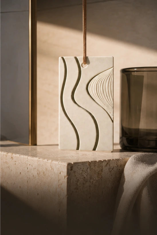 Natural Gypsum hanging fragrance plaque in a sunlit limestone and smoked-glass interior