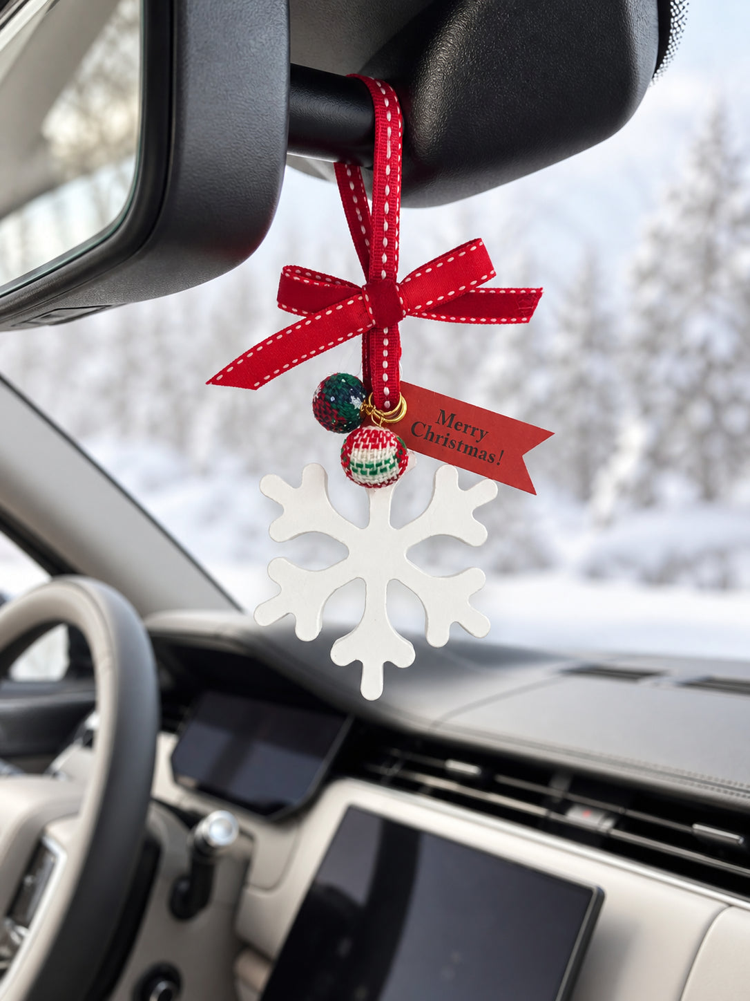 Winter snowflake ornament hanging from a ribbon loop behind the mirror in a parked Range Rover SV