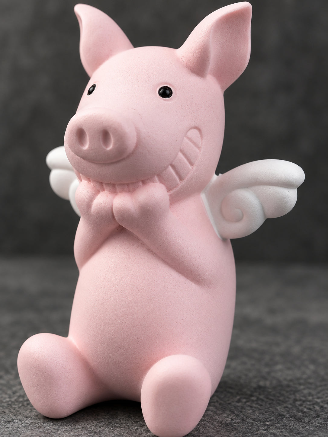 Close view of the Wish Pig's white curled wing, carved smile and clasped hands