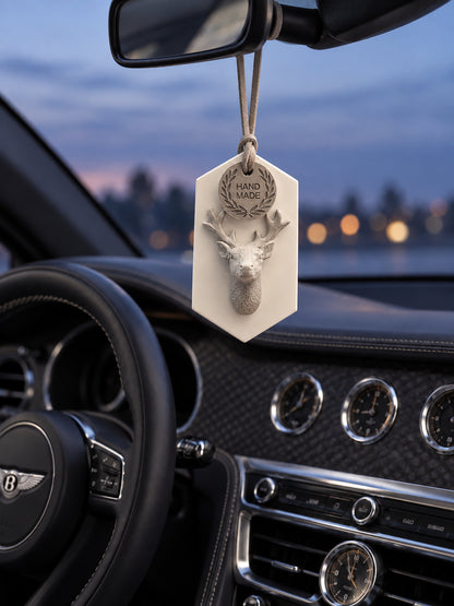 Gray stag medallion hanging from the mirror support in a parked Bentley Flying Spur at blue hour