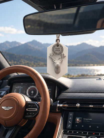 White plaque and gray stag ornament with its cord passing behind the mirror in an Aston Martin DB12
