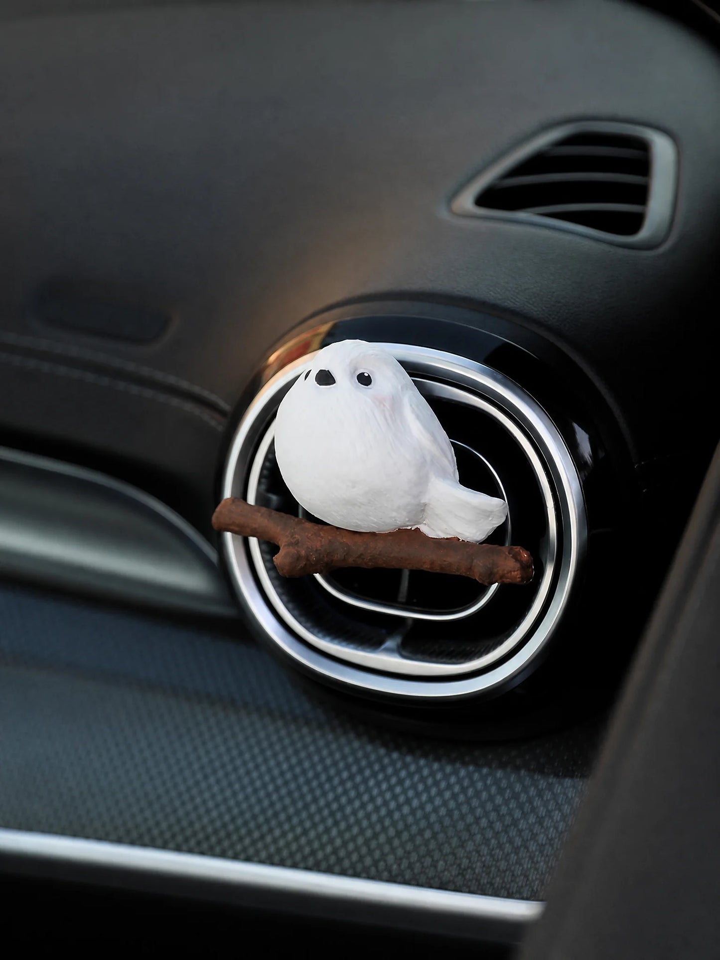 White chubby bird car air freshener clipped on black vent
