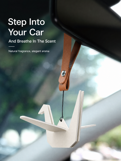 White origami crane air freshener hanging inside a beige car interior